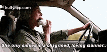 a woman is driving a car and smiling while eating a sandwich .