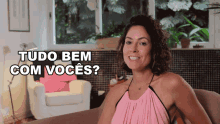 a woman is sitting on a couch with the words tudo bem com voces behind her