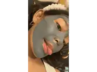 a woman with a blue mask on her face sticking out her tongue