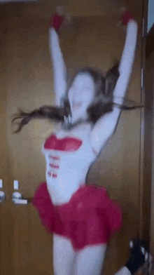 a woman in a red skirt and white top is dancing with her arms in the air .