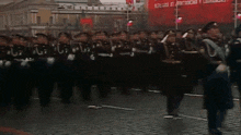 a group of soldiers march down a street in front of a red sign that says " lenin "