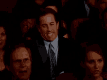 a man in a suit and tie is waving his hand in the audience .