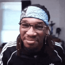 a man wearing glasses and a bandana is smiling and making a funny face .