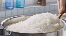 a bowl of white rice is being stirred with a wooden spoon