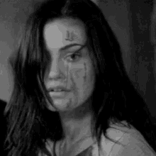 a black and white photo of a woman with a tattoo on her forehead .