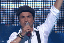 a man singing into a microphone with the number 16 in the corner