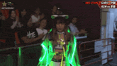 a woman in a neon green outfit stands in front of a crowd and a sign that says #stardom on it