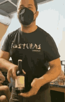 a man wearing a mask is holding a bottle of vino