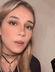 a close up of a woman 's face with a choker necklace .