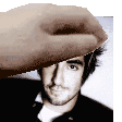 a hand is holding a man 's head in front of a picture .