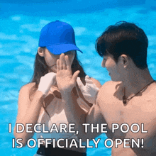 a man and a woman are standing in a pool and the woman is covering her face with her hand