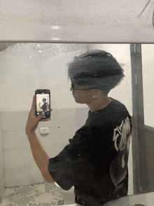 a man in a black shirt taking a picture of himself in a mirror