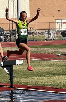 a woman is jumping over a hurdle on a track and field track .