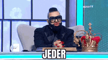 a man with a beard and red lips is sitting in a chair with a crown on his desk .