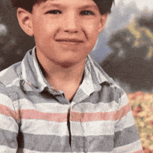 a young boy is wearing a striped shirt and smiling
