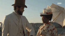 a man in a top hat stands next to a woman holding an umbrella with hbo written on the bottom right
