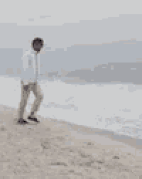 a man is standing on a beach near the ocean