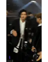 a man in a suit is dancing in front of a microphone while another man holds a camera .