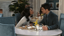 a man and a woman are sitting at a table kissing .