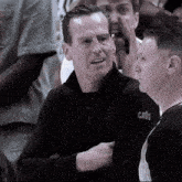 a man wearing a cavs jacket talks to a referee