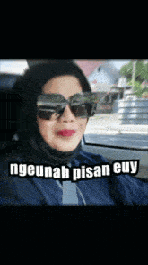 a woman wearing sunglasses and a hijab is sitting in a car