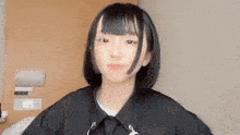 a young girl with short black hair is standing in front of a door .