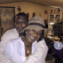 a man wearing a hat is hugging a woman who is smiling