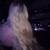 a woman with blonde hair is standing in a dark room