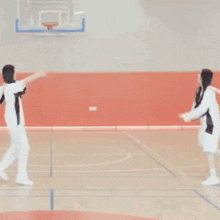 two women in white clothes are dancing on a basketball court