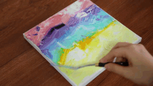 a person is painting a rainbow with a palette knife