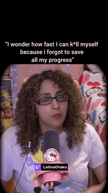 a woman wearing glasses and a hello kitty shirt stands in front of a pink hello kitty microphone