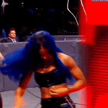 a woman with blue hair is standing in front of a red wall that says thenextbigthing
