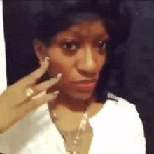 a woman in a white shirt is making a funny face with her hand on her face