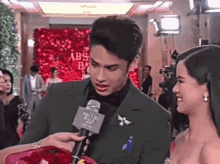 a man in a green suit is talking into a microphone with abs cbn written on it