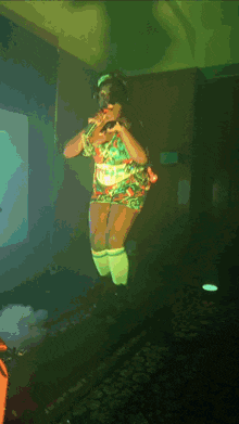 a woman is singing into a microphone in a green room