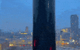 a view of a city from a window with a tall building in the foreground