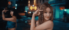 two women are dancing in front of a neon sign that says ' i ' on it