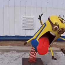 a statue of a minion with a red tongue sticking out is sitting on a spring .