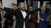 a man with his arms outstretched stands in front of a group of people with the word zero on the bottom right