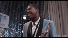 a man in a suit and tie is holding a trophy and laughing .