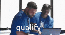 a man in a blue shirt is looking at a laptop .