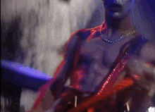 a shirtless man is playing a guitar in a dark room