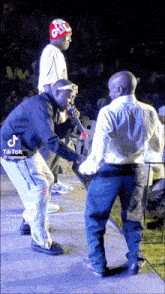 a man in a red hat is standing next to another man on a stage