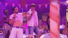 a group of men are dancing on a stage in front of a crowd of people .