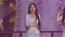 a woman is standing on a stage in front of a purple wall .