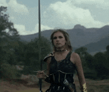 a woman is holding a sword in a field .