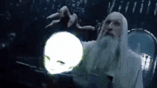 a man with a beard is holding a glowing ball in his hand .