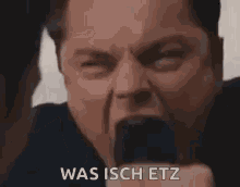 a close up of a man 's face with his mouth open and the words `` was isch etz '' written next to him .