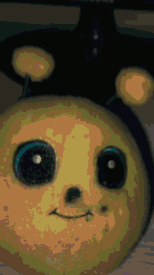 a close up of a stuffed animal that looks like a bee with big blue eyes
