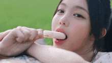a woman is eating an ice cream bar with a green background